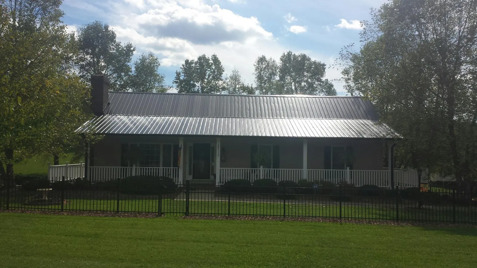 Gray metal roof on a brick ranch with a full width front porch — Gutter Guard Installation work by our crew in Mapleton