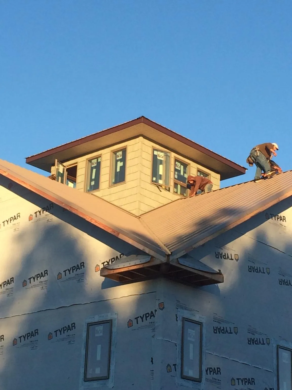 Roofers working around a rooftop cupola on a new metal roof at sunset — Roof Waterproofing in Mapleton by Roofing Brothers